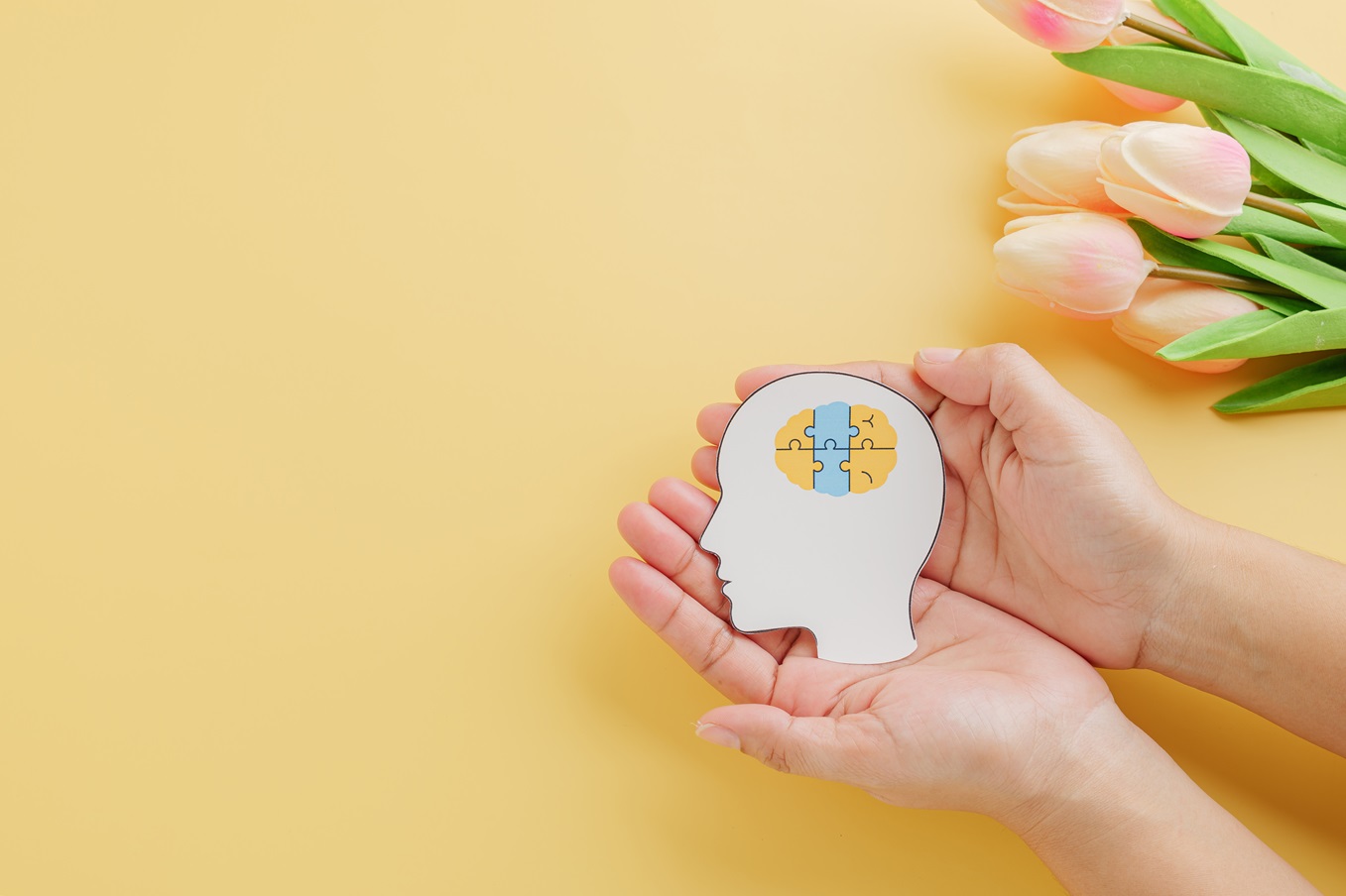 hands holding brain jigsaw in head paper cut symbo