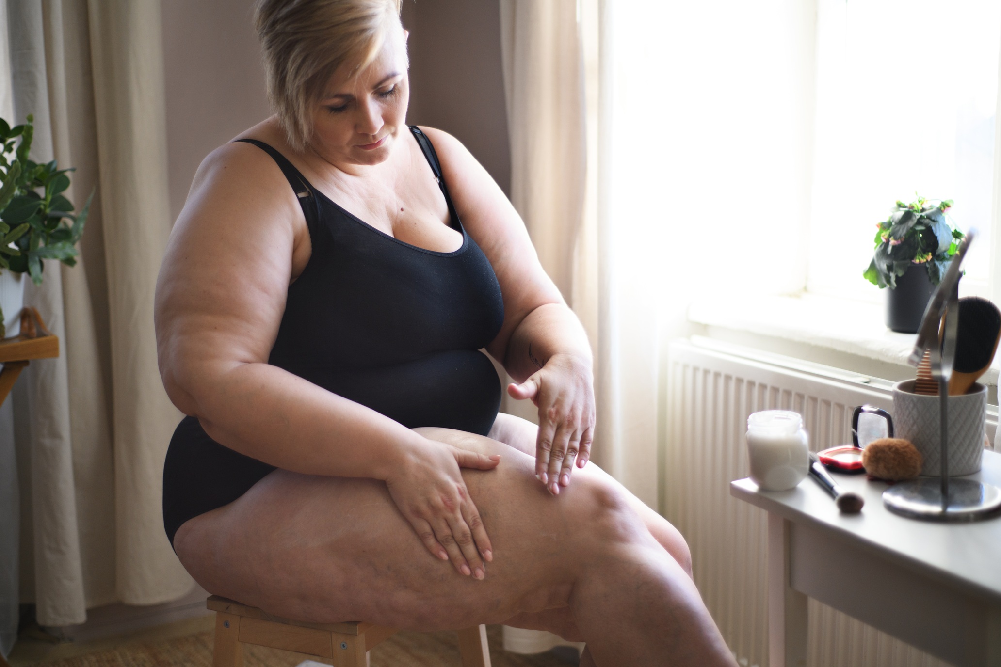 overweight woman sitting and applying cream on her