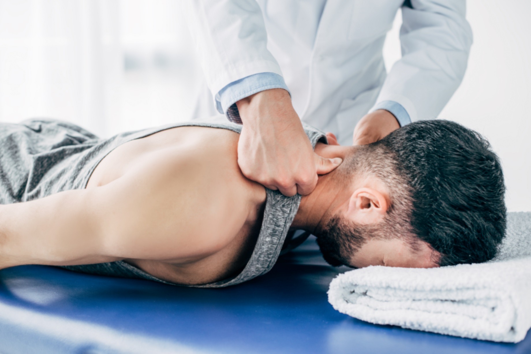 chiropractor massaging neck of man lying