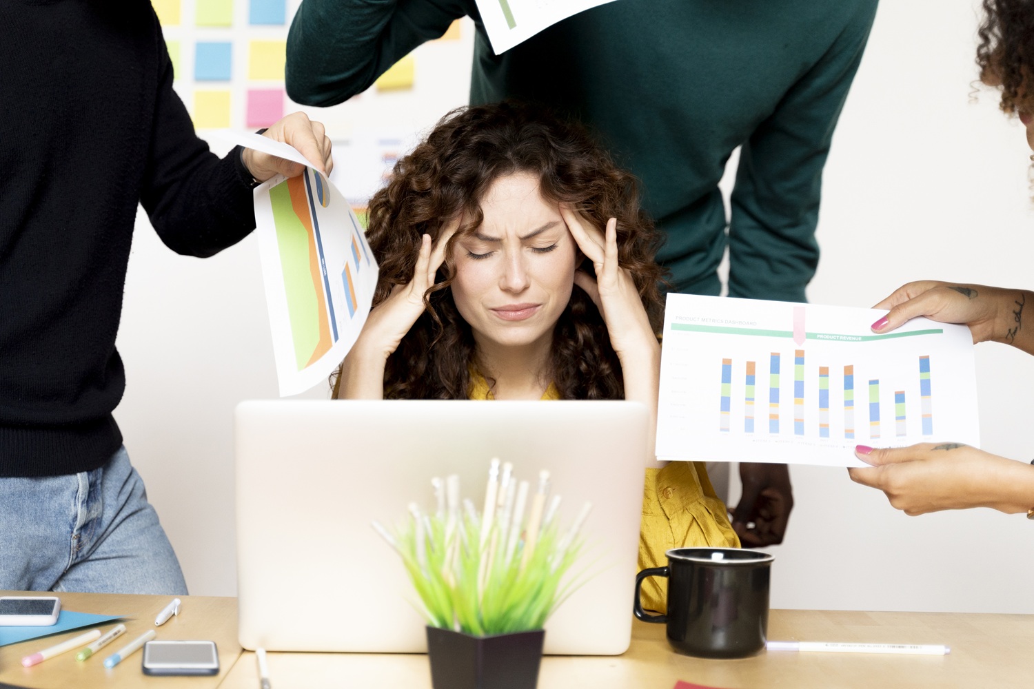 stressed woman siting at desk in office surrounded
